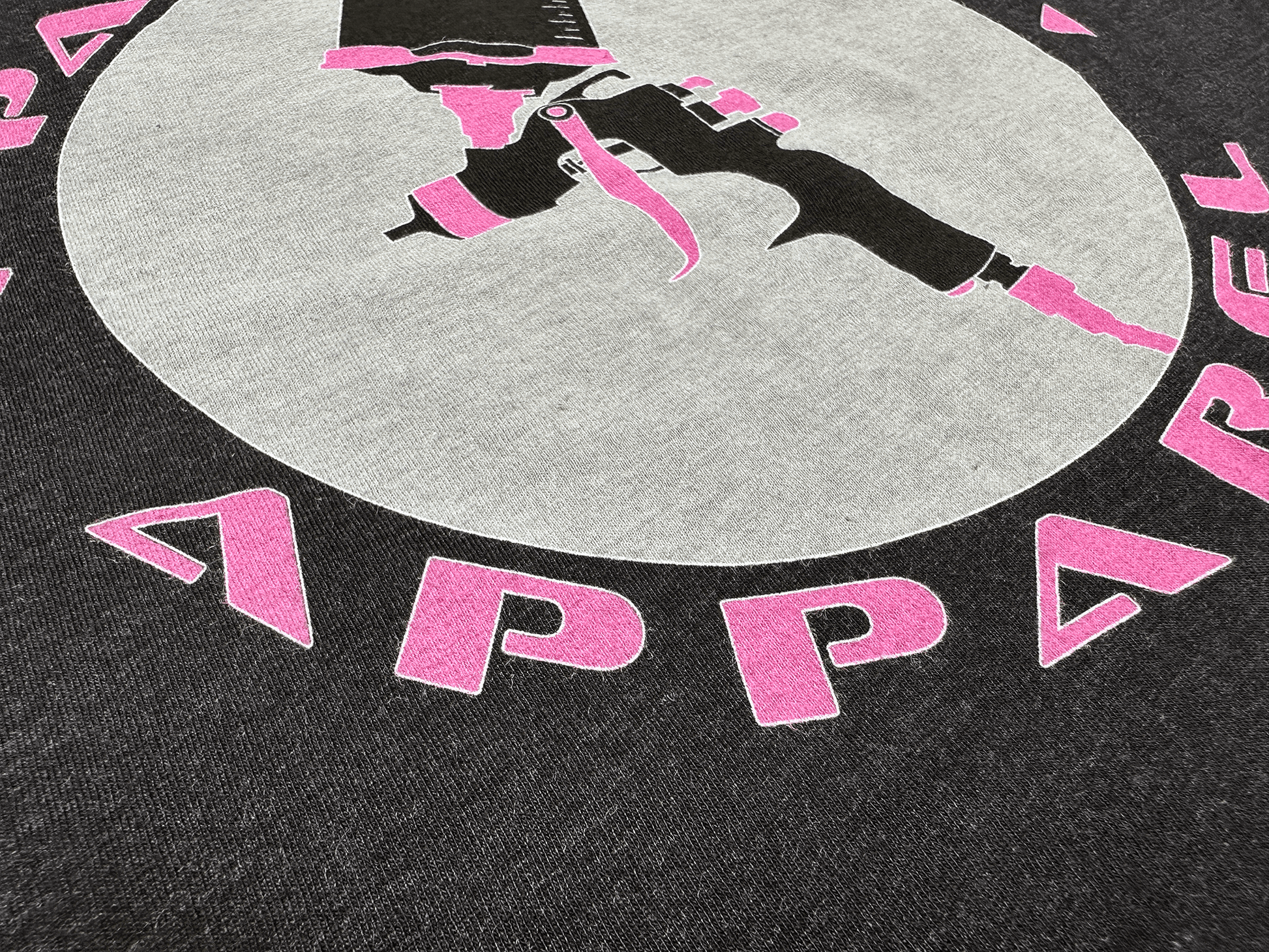 Pink and Black PSA Logo on Ladies' Black T-Shirt Close Up View of Logo Tilted Left